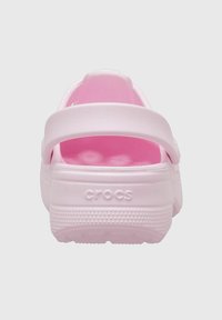 Różowy piankowy klapek bez pleców z teksturowanym paskiem, wyposażony w wyściółkę dla komfortu oraz wypukłe kropki. Na pięcie wytłoczone logo "CROCS".