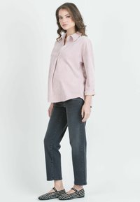 Vaaleanpunainen nappipaita rentoa leikkausta, yhdistettynä tummanharmaisiin farkkuihin ja mustiin ballerinoihin, joissa on valkoisia niittejä.