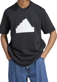 Czarny bawełniany T-shirt z wyrazistym białym logo adidas w kształcie góry. Luźny krój z krótkimi rękawami.