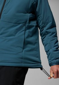 Türkise isolierte Jacke mit einem Reißverschluss vorne und elastischem Kordelzug am Saum, ausgestattet mit einer glatten Textur und gesteppten Paneelen.