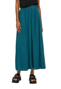 Teal maxi rok gemaakt van lichtgewicht stof, met een geplooide tailleband en vloeiende draping, gecombineerd met dikke zwarte plateau sandalen.