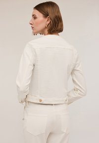Vit beskuren denimjacka med knäppning, långa ärmar och en slät textur. Bakifrån framhäver den en minimalistisk design med en enkel finish.