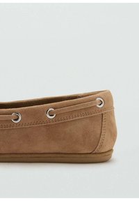 Suède instapschoen in tan kleur, voorzien van zilveren veteroogjes aan de bovenkant en een platte bruine zool, met een gladde textuur en afgeronde vorm.