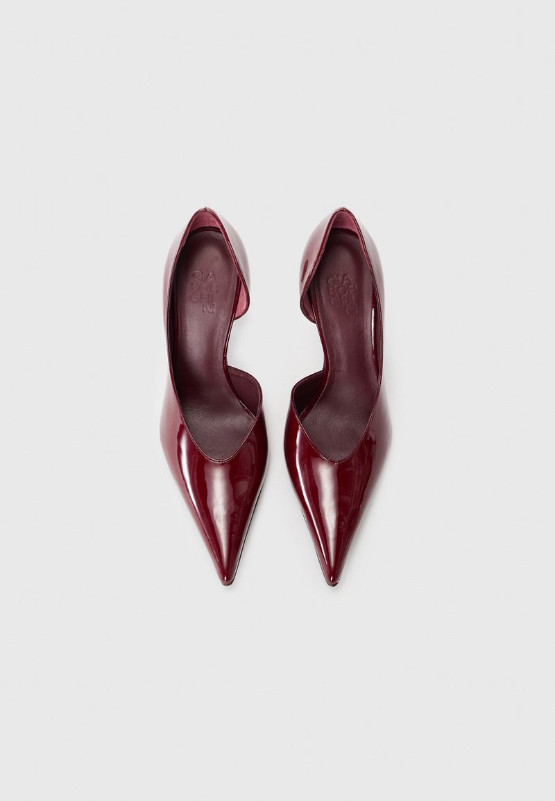 Bordeauxfarbene Lackleder-High Heels mit spitzem Zehenbereich und tiefem Schnitt an den Seiten. Glatte Textur mit glänzender Oberfläche.