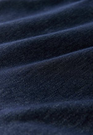 Tmavě indigový džínový materiál s hladkou texturou, obsahující jemné diagonální vzory tkaní a mírný lesk, zobrazující měkké vlnky.