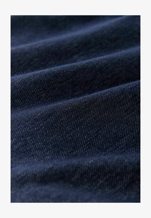 Ciemny jeansowy materiał w kolorze indygo o gładkiej fakturze, z subtelnymi ukośnymi wzorami tkaniny i delikatnym połyskiem, prezentujący miękkie zmarszczenia.
