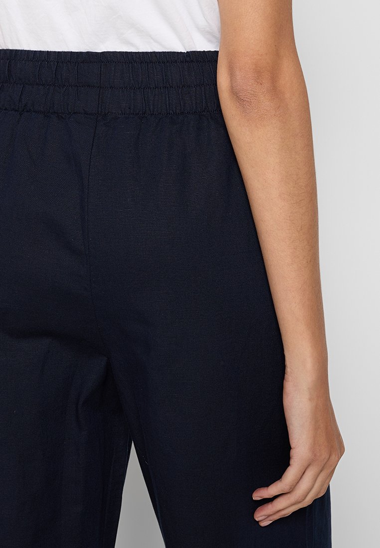 Navyblaue Hose mit elastischem Bund und glatter Textur. Der Stoff wirkt leicht und atmungsaktiv. Keine sichtbaren Muster oder Akzente.