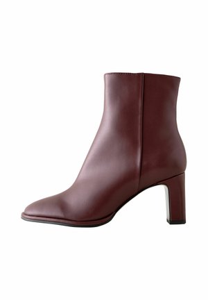 Bottine en cuir marron avec bout pointu et talon bloc, fermeture éclair latérale, texture lisse et design moderne élégant.