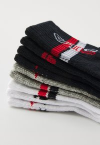 Calze a maglia in nero, grigio e bianco, con accenti e motivi colorati. Texture morbida con design a coste.