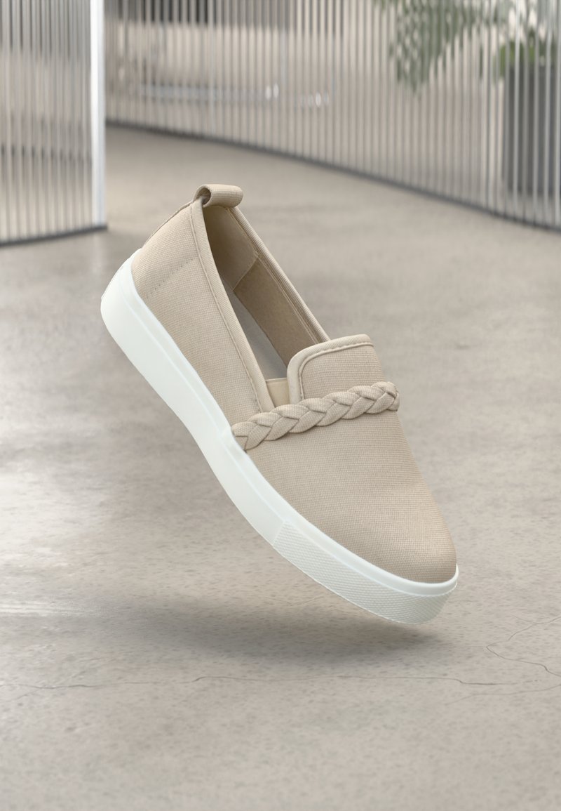 Beige slip-on shoe made of canvas with a braided detail across the front and a white rubber sole. Minimalistic design with elastic sides.