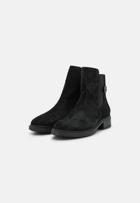 Botines de ante negros con paneles laterales elásticos, tacón bajo y un detalle dorado en el lateral. Textura suave y diseño clásico.