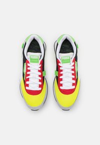 Bunte Sneaker mit Mesh- und Synthetik-Obermaterial. Verfügt über gelbe, rote, grüne und schwarze Einsätze, weiße Schnürsenkel und eine strukturierte Gummisohle.