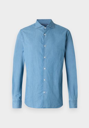 Chemise en denim bleu clair à manches longues, avec fermeture boutonnée devant, col classique et texture lisse. Dotée de boutons blancs le long de la patte de boutonnage.