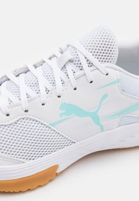 Białe buty sportowe z siateczkową cholewką, turkusowymi akcentami i gumową podeszwą. Podkreślone wyraźnym logo Puma.