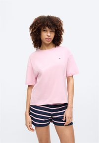 Rosa Baumwoll-T-Shirt mit lockerem Schnitt, kurzen Ärmeln und einem kleinen Logo auf der Brust, kombiniert mit marineblauen Shorts mit Streifen.