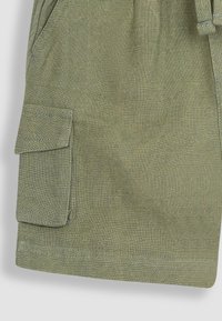 Olivov�ě zelené cargo šortky vyrobené z texturované látky. Mají náprsní kapsu s klopou a látkový pásek v pase.