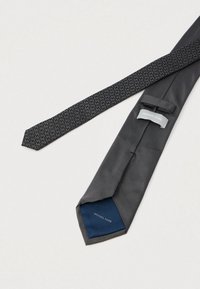 Texturált mintájú fekete nyakkendő, amelynek egy része egyszínű sötétszürke. Az alsó oldalon található logócímke "Michael Kors" felirattal. Sima anyagú kivitel.