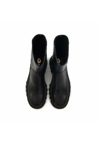 Paire de bottines en cuir noir avec des bouts carrés arrondis et des semelles épaisses en caoutchouc, vues de dessus sur un fond blanc.