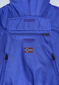 Modrá nepromokavá bunda s kapsou na zip, suchými zipy a nášivkou s norskou vlajkou. Hladký povrch s kapucí.