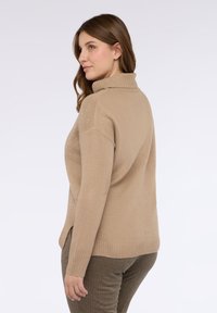 Beige rolák s texturovanými akcenty, žebrovanými lemy a volnějším střihem. V kombinaci s texturovanými hnědými kalhotami.