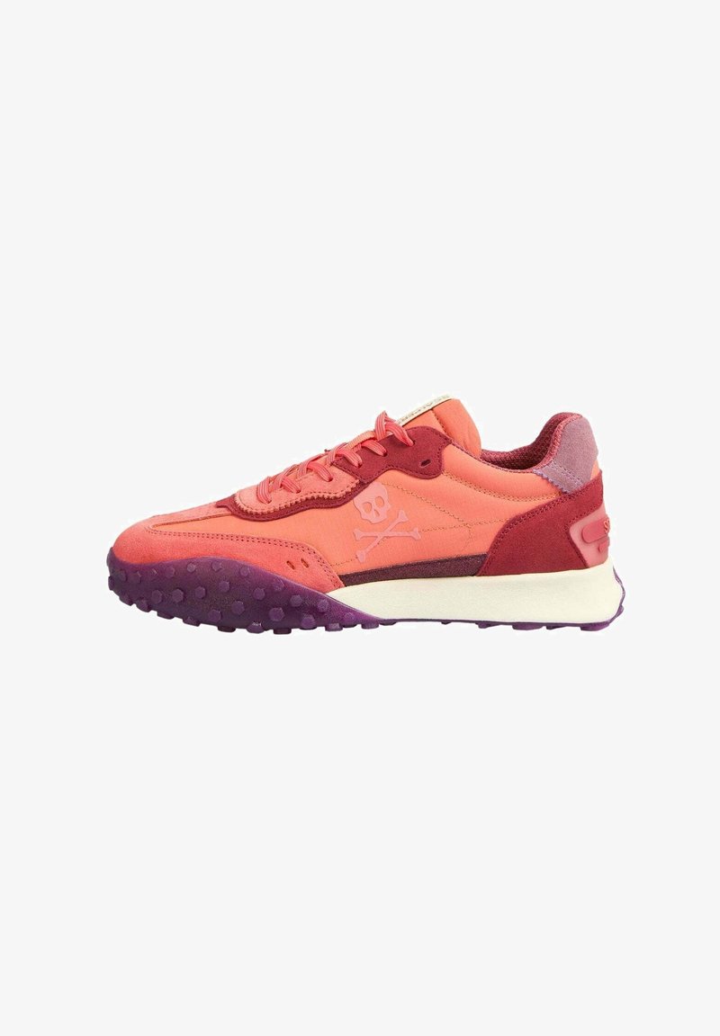 Zapatilla rosa y roja con un upper texturizado, que presenta un logo de calavera y huesos cruzados, y una suela de color púrpura con motas. Diseño ligero.