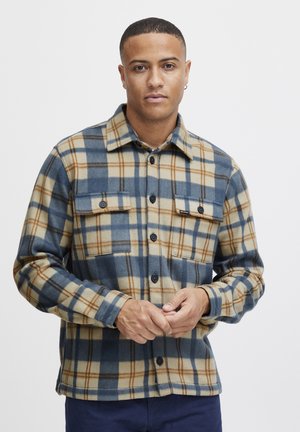 Ruuduline flanellshirt siniste, beežide ja pruuni värviga. Omab kahte rinna taskut, nööbiga esist ja krae. Pehme tekstuur.