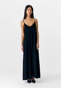 Abito maxi nero con spalline sottili, scollatura a V e silhouette fluida. Tessuto liscio e design minimalista.