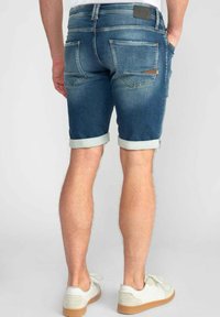 Denim shorts met een opgerolde zoom, middelblauwe wassing, met achterzakken en een logo-etiket; zachte textuur en aansluitend ontwerp.