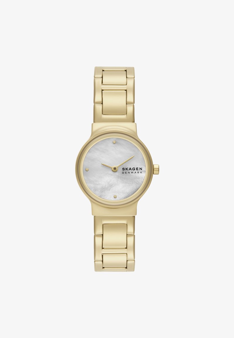 Złoty metalowy zegarek na rękę z okrągłą kopertą, białą tarczą z masy perłowej i minimalistycznymi znacznikami godzinowymi. Posiada bransoletę złączoną z błyszczącym wykończeniem.