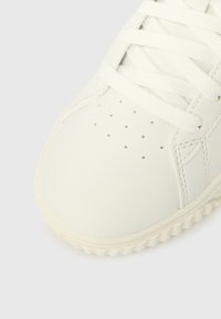 Άσπρο δερμάτινο παπούτσι με στρογγυλεμένη μύτη, υφή στο σχέδιο με κορδόνια, μικρές οπές για αερισμό και λαστιχένια  σόλα με κυματιστή όψη.