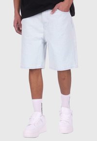 Light blue denim shorts with a relaxed fit, featuring side pockets and stitched seams, worn with white sneakers and striped socks.