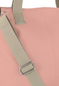 Sac fourre-tout en cuir rose avec une finition texturée, équipé d'une sangle en tissu gris clair et de ferrures métalliques argentées pour l'attachement.