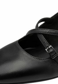 Černá kožená botka s kulatou špičkou, s křížovým páskem a nastavitelnou sponou. Hladký povrch s minimem švů.