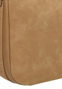 Hellbraune Crossbody-Tasche aus Leder mit einer glatten, samtigen Textur, runder Form und minimalistischer Gestaltung. Dezente Nähedetails an den Kanten.