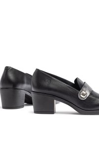 Zapatos de tacón de cuero negro con punta redondeada, un acento decorativo de hebilla y un upper texturizado. Tacón bajo moderado, acabado suave.