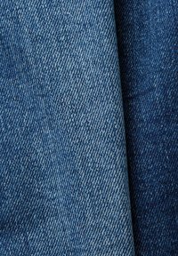 Tissu en denim aux nuances variées de bleu, présentant une armure sergé classique et une texture lisse, avec une décoloration subtile et des motifs de côtes diagonales.