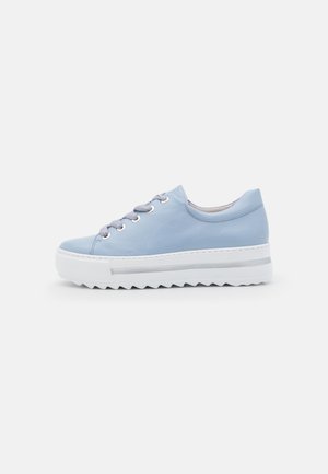 Lyseblå lavtop sneaker med hvid tyk ribbet sål og grå snørebånd på en ensfarvet hvid baggrund.