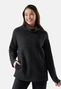 Pullover grigio in pile con colletto alto, maniche lunghe e tasche laterali. La texture è morbida e leggermente pelosa.