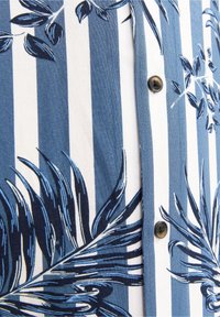 Tissu à rayures verticales bleues et blanches avec des motifs de feuilles tropicales bleu foncé et des boutons marron sur le devant d'une chemise.
