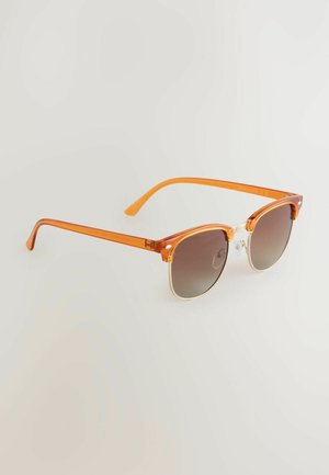 Oranžové transparentní sluneční brýle s kulatými obrubami, přechodovými hnědými skly a štíhlými oranžovými stranami s průhlednými akcenty na pantích.