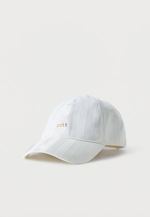Casquette de baseball blanche rayée avec visière incurvée et petit logo doré "BOSS" à l'avant, sur fond blanc uni.
