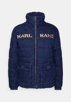 Veste matelassée en denim bleu marine avec un col haut, fermeture éclair et deux poches avant. Broderie dorée "KARL" et "KANI" sur la poitrine. Détails de couture.
