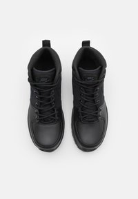 Sorte høyhælte sneakers med en glatt syntetisk overdel, teksturert mesh krage og sorte lisser; har logoer på tungen og siden.