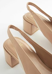 Beige slingback-kengät, joissa on lohkarekorko, sileää synteettistä materiaalia, pyöristetty kärki ja vähäisiä ompelutietoja.