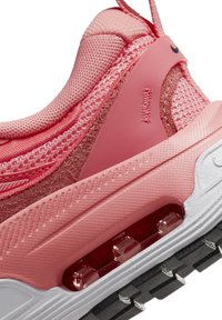 Nike-tossut, joissa on vaaleanpunainen verkkomateriaali, sileät muoviosat, näkyvä ilmanvaimennus ja teksturoitu valkoinen ja musta kumipohja.