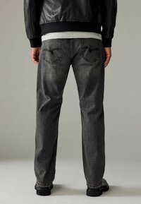 Donkergrijze denim jeans met een ontspannen pasvorm, voorzien van achterzakken met een gestikt ontwerp en een subtiel gestructureerde stofafwerking.