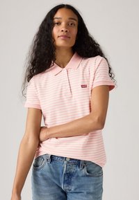 Polo a righe rosa e bianche realizzato in cotone morbido, con colletto, maniche corte e un piccolo logo rosso Levi's sul petto.