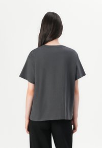 Kurzärmliges T-Shirt mit Rundhalsausschnitt aus festem, dunklem grauen Baumwollstoff. Lockere Passform mit geradem Saum und ohne sichtbare Designs oder Akzente.