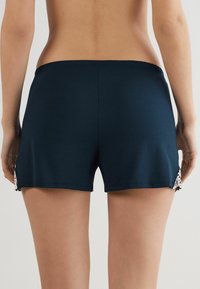 Mörkblå shorts i mjukt, elastiskt tyg. Har spetsdetaljer på sidan och en elastisk midja för komfort.