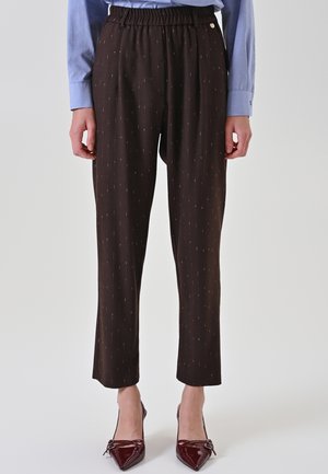 Woman wearing black slim-fit pants with subtle pinstripes, a light blue long-sleeve shirt, and burgundy pointed-toe heels.